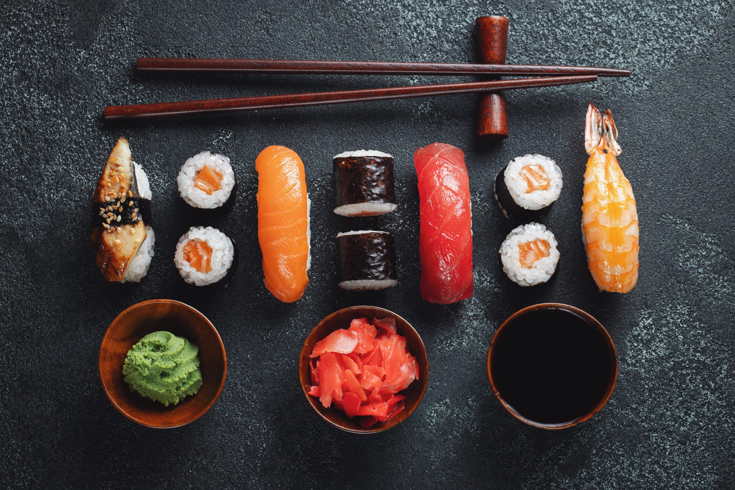 Set of sushi and maki on stone table.